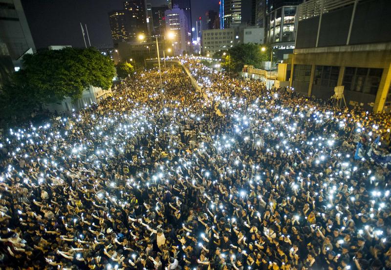 Protestors and student demonstrators hold up their cellphones in a display of solidarity during a protest outside the headquarters of Legislative Council in Hong Kong on September 29, 2014.