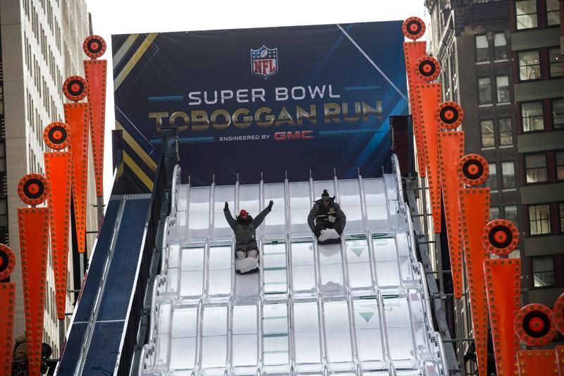 Sliding down the 'Super Bowl Toboggan Run,' set up as a part of Super Bowl Boulevard
