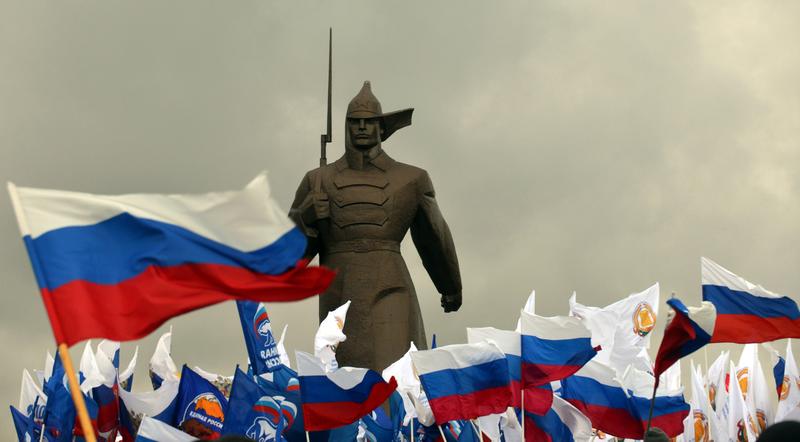 Pro-Kremlin activist hold Russian flags near a monument to Red Army soldier as they rally in the southern Russian city of Stavropol, on March 18, 2014, to celebrate the incorporation of Crimea.