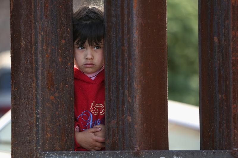 A child on the Mexican side of the U.S.-Mexico border fence looks into Arizona during a special 'Mass on the Border' on April 1, 2014 in Nogales, Arizona.