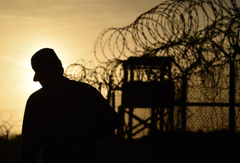 A U.S. soldier walking next to the razor wire-topped fence at the abandoned 'Camp X-Ray' detention facility at the US Naval Station in Guantanamo Bay, Cuba, April 9, 2014.