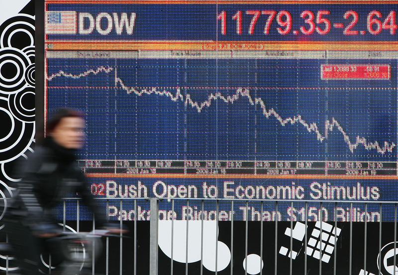 A cyclist passes a financial display screen showing the FTSE 100 on January 22, 2008 in West London.