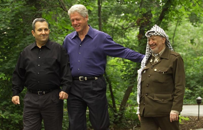 Then President Clinton, center, accompanied by Israeli Prime Minister Ehud Barak, left, and Palestinian leader Yasser Arafat, right, walk on the grounds of Camp David, Md.