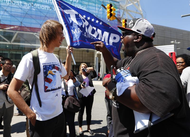 Zack W., left, listens to Maurice Hardwick at a protest while Republican presidential candidate Donald Trump delivered an economic policy speech to the Detroit Economic Club in Detroit, Monday, Aug. 8
