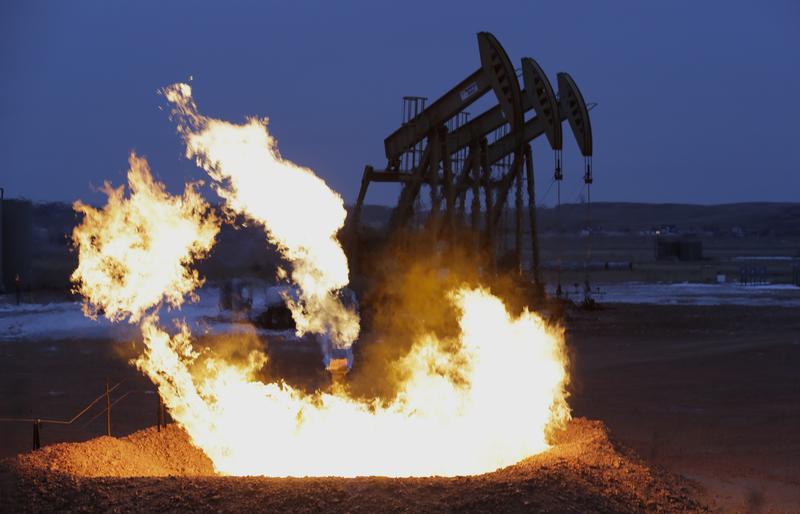 Flames erupt from a natural gas flare near oil pump jacks in the Watford City, N.D. area.
