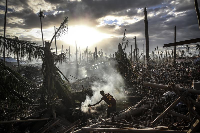 A man fans flames on a fire Tanauan on November 19, 2013 in Leyte, Philippines. Typhoon Haiyan ripped through Philippines, leaving thousands dead and hundreds of thousands homeless.