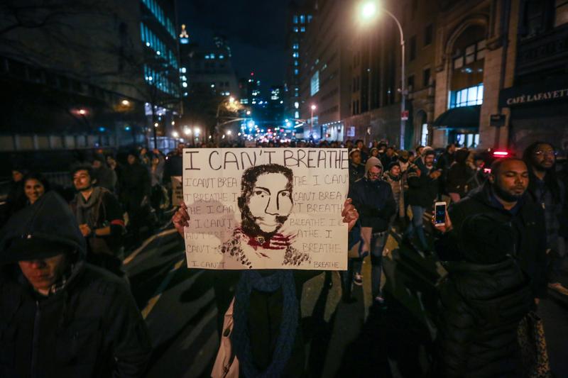 A protester holds up a sign with Eric Garner's portrait and last words.