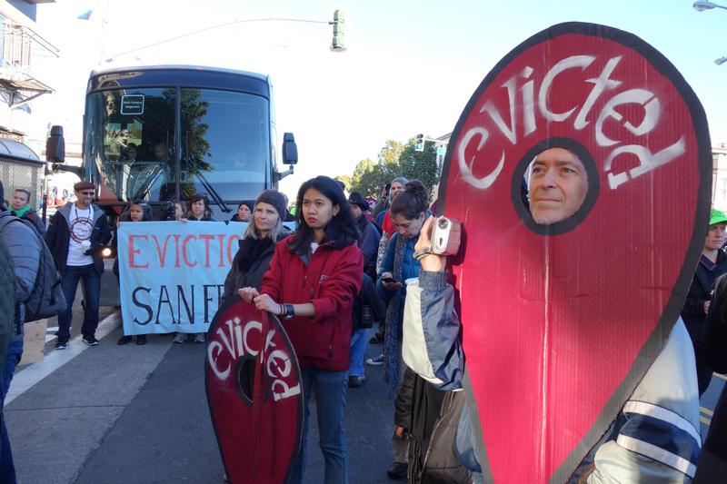 People blocking an Apple bus hold google maps style eviction markers as a Google bus passes on Valencia St on December 9, 2013.