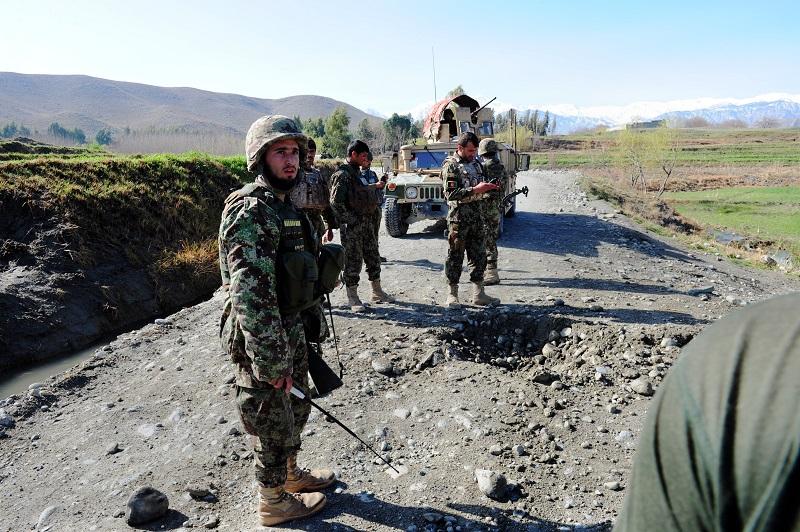 On 3/18/14 an Afghan soldier (L) attached to the 4th Brigade, 201 Army Corps of the Afghan National Army (ANA) stands next to a crater after an IED was triggered by insurgents using a mobile phone.