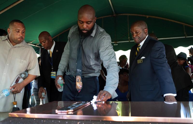 Michael Brown Sr. wipes the top of the vault during the funeral for his son Michael Brown at St. Peters Cemetery on August 25, 2014 in St. Louis Missouri.