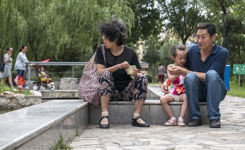 An elderly couple, who left their hometown to live in Beijing, takes care of their only grandchild playing in their residential community, 2015/08/14.