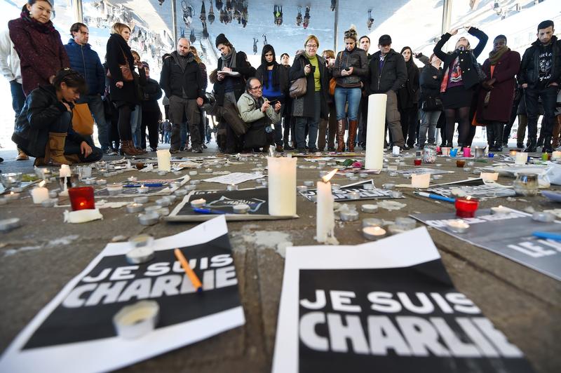 People gather next to signs reading ''I am Charlie'' and candles placed on the ground, after observing a minute of silence in the old Harbor in Marseille on January 8, 2015 for the victims.