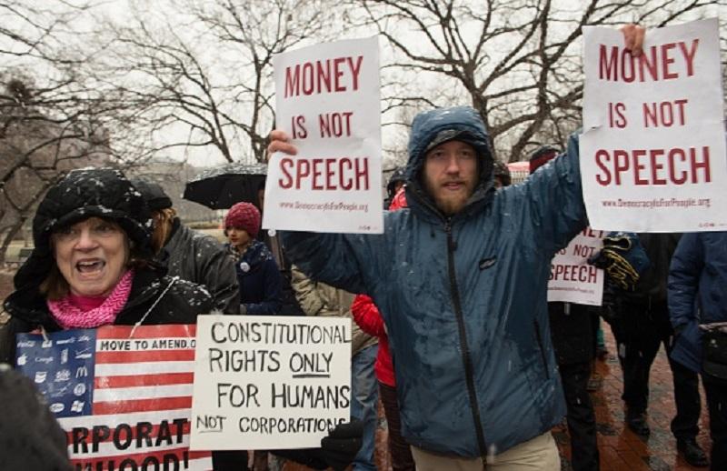 Demonstrators march in the snow through Lafayette Park, outside the White House, to the US Chamber of Commerce during a rally against the Supreme Court's decision in favor of Citizens United.