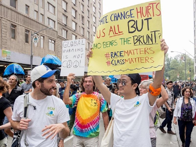 A protestor holding a sign stating that consequences of climate change will be felt more by lower class in People's Climate March, in New York City.