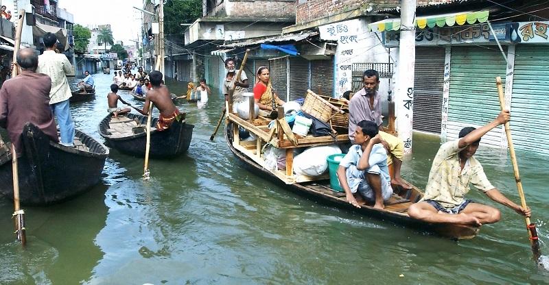 Bangladeshi flood victims use boats laden with their possessions to navigate flooded city streets in Dhaka, 26 July 2004.