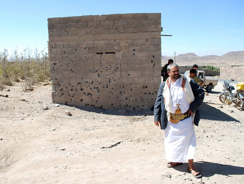 Himyar al Qadhi stands next to a building pockmarked by damage from the drone strike that killed his brother Adnan, who was targeted for his alleged ties to AQAP.