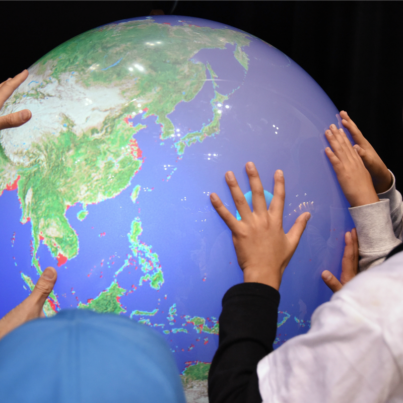 Schoolchildren touch an electronic globe to learn the rise in sea levels by global warming in Tokyo.