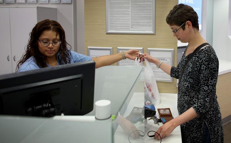 Mercedes Betaneo (L), a pharmacy technician for Walgreens, sells medicine at the Walgreens pharmacy to Christine Matthews who was using the insurance she purchased under the Affordable Care Act.