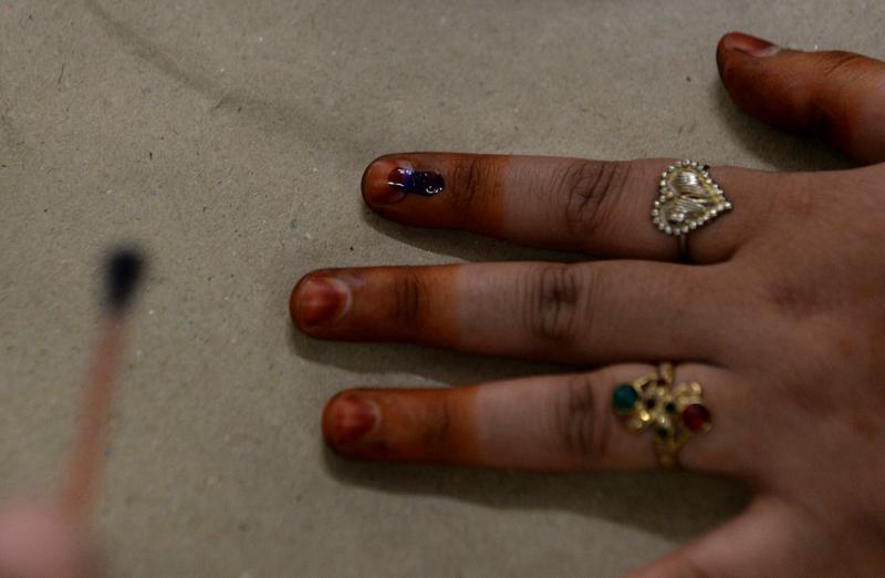 An Indian election officer marks the finger of a voter with ink at a polling station in New Delhi.