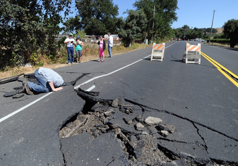 Nicholas George looks under a buckled highway just outside of Napa, California after earthquake struck the area in the early hours of August 24, 2014.