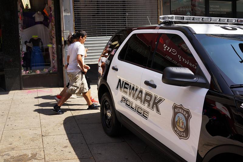 People walk by a police car in downtown on May 13, 2014 in Newark, New Jersey.