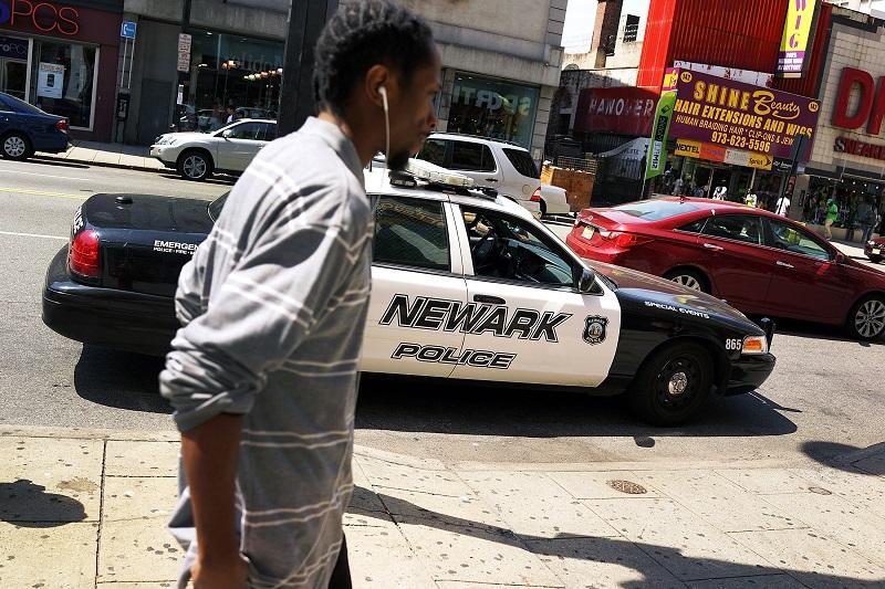 A man walks by a police car in downtown on May 13, 2014 in Newark, New Jersey.