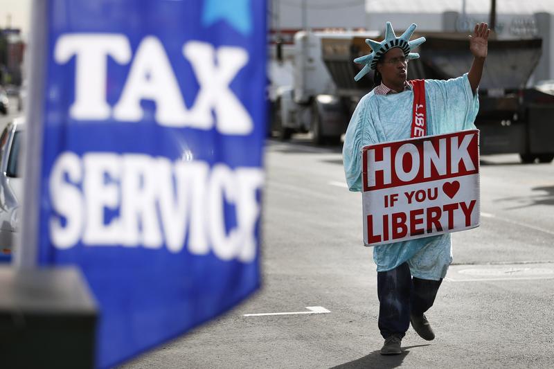 A man dressed as the Statue of Liberty advertises a tax service.