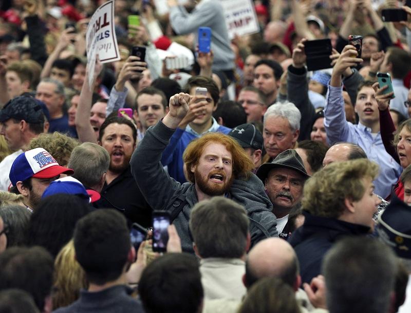 In this Tuesday, March 1, 2016 file photo, a protester is escorted out of a rally for Republican presidential candidate Donald Trump in Louisville, Ky.