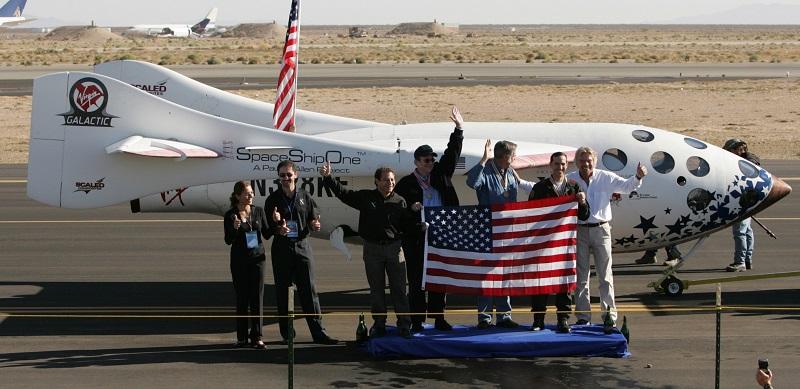 SpaceShipOne and X Prize team members pose with a U.S. flag carried aboard the spacecraft after its successful flight into space and landing at Mojave, Calif., Airport Monday, Oct. 4, 2004.