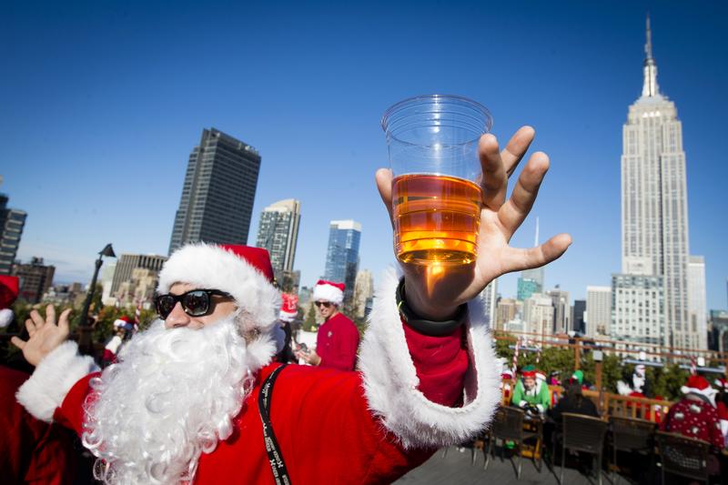 A man dressed as Santa Claus holds a beer as he and others participate in SantaCon on a rooftop bar Saturday, Dec. 13, 2014, in New York.