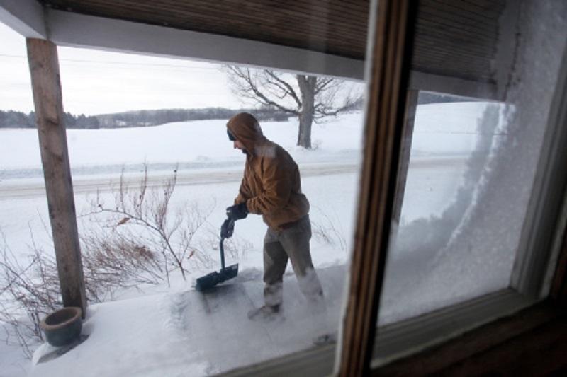 Man, 30 years old, shoveling snow off his porch, Cooperstown, New York.