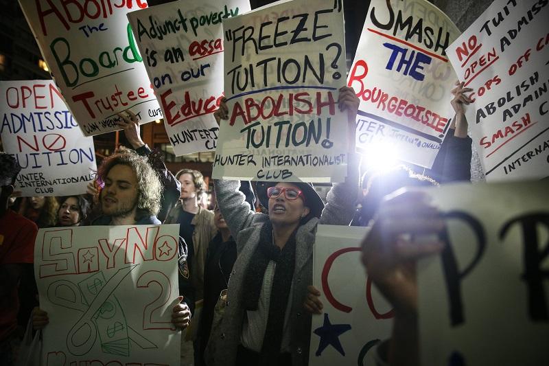 Students hold placards as they stage a demonstration at the Hunter College to protest ballooning student loan debt for higher education and rally for tuition-free public colleges.