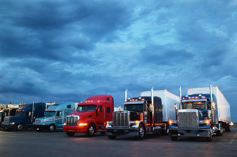 Semi-trucks parked at truck stop, dawn.