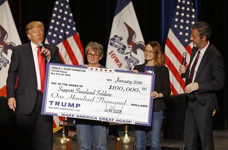 In this Jan. 31, 2016 file photo, Republican presidential candidate Donald Trump, left, presents a check to members of Support Siouxland Soldiers during a campaign event at the Orpheum Theatre in Siou