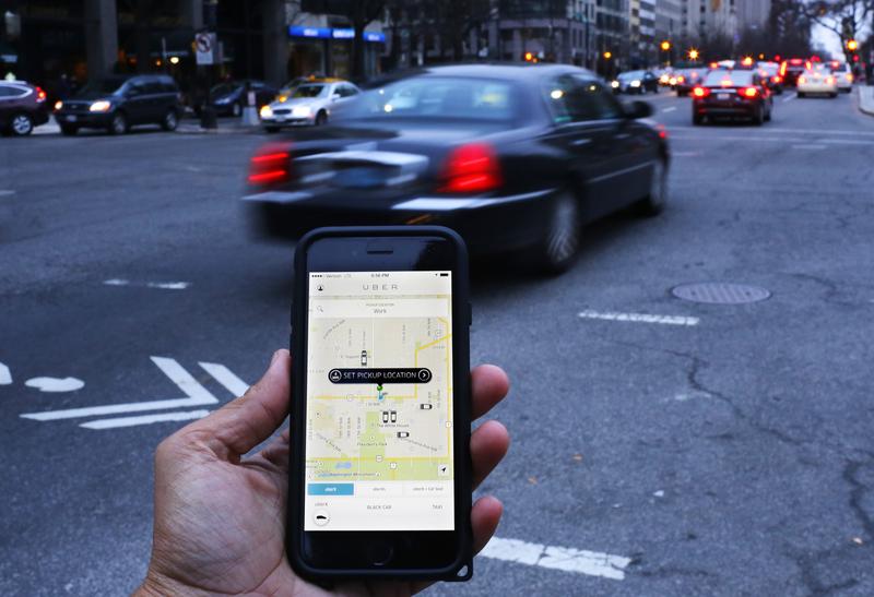 An UBER application is shown as cars drive by in Washington, DC on March 25, 2015.